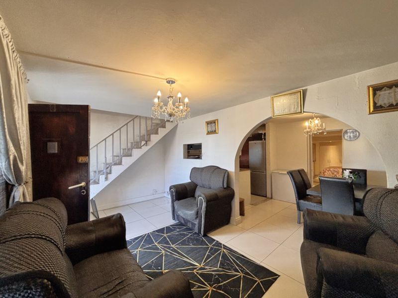 Open plan living area featuring tiled flooring, a central archway, and a staircase leading to the upper level.