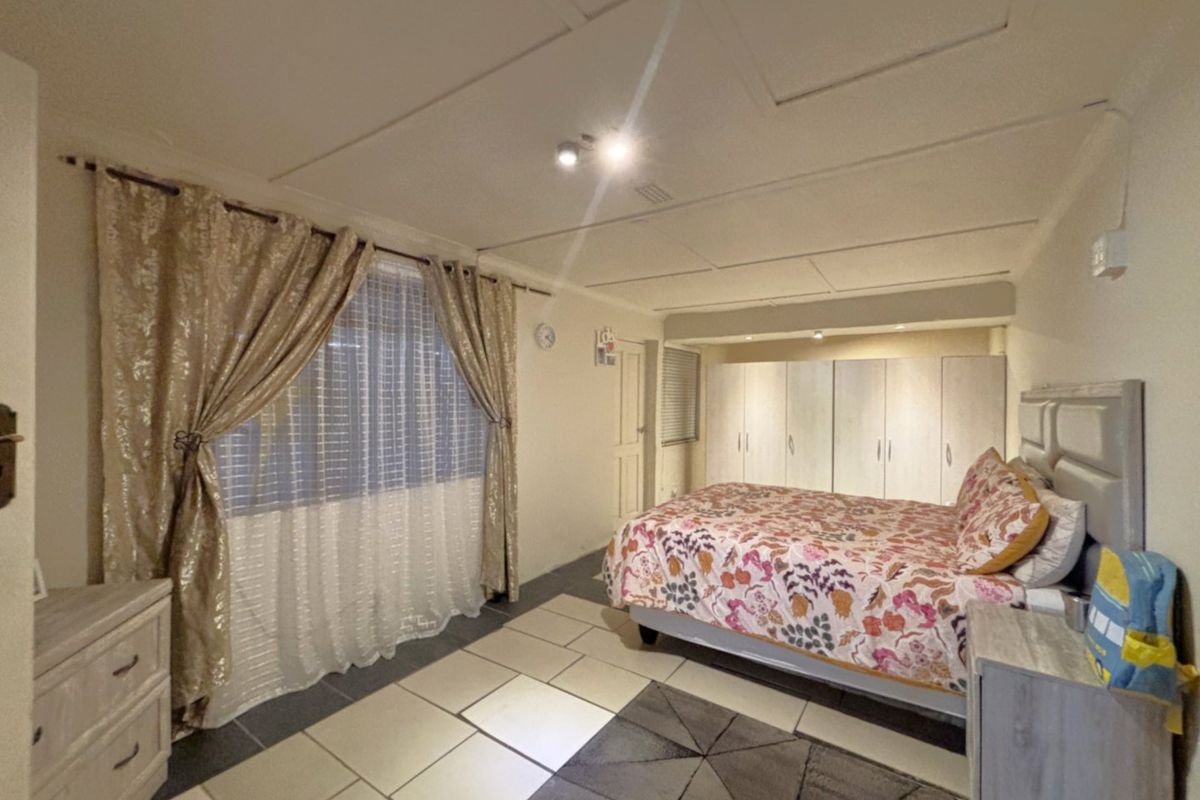 Spacious bedroom featuring built-in cupboards, tiled flooring, and a neutral ceiling finish, offering a functional layout with ample storage space.