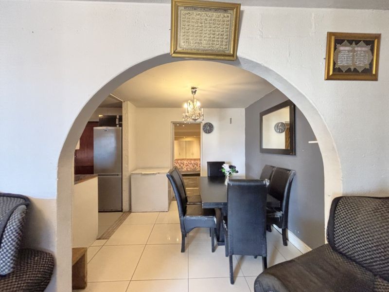 Dining area featuring a prominent arched entryway, tiled flooring, and a central chandelier, connecting to the kitchen and adjacent living spaces.