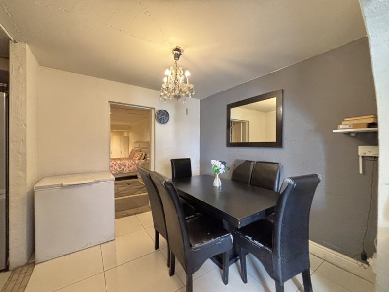 Dining area featuring tiled flooring and a central light fixture, providing access to an adjacent bedroom.