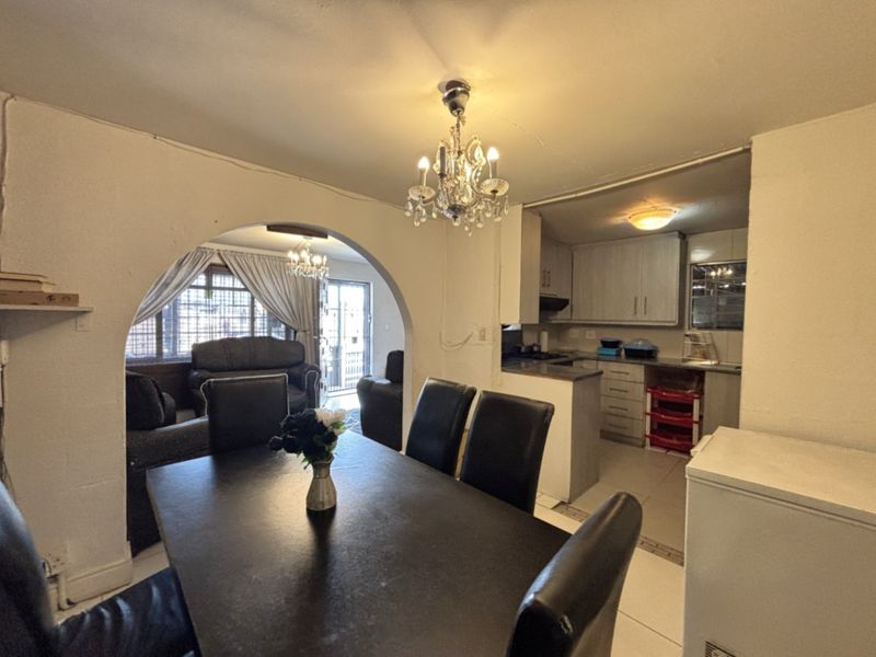 Open plan living and dining area featuring a decorative archway, tiled flooring, and an adjoining kitchen with built-in cabinetry.
