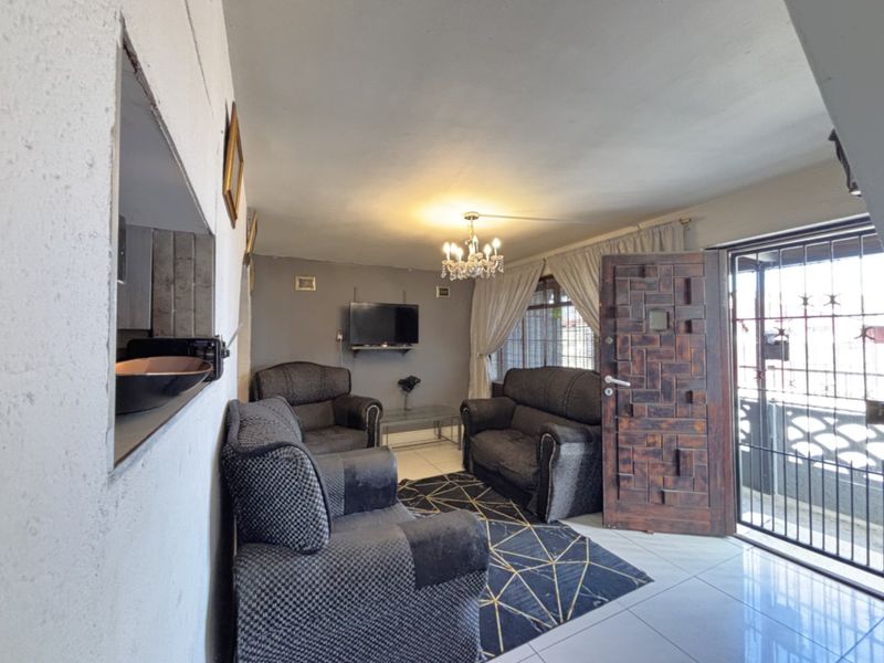 Living room featuring tiled flooring, a decorative timber entrance door, and a pass-through window connecting to the adjacent space.