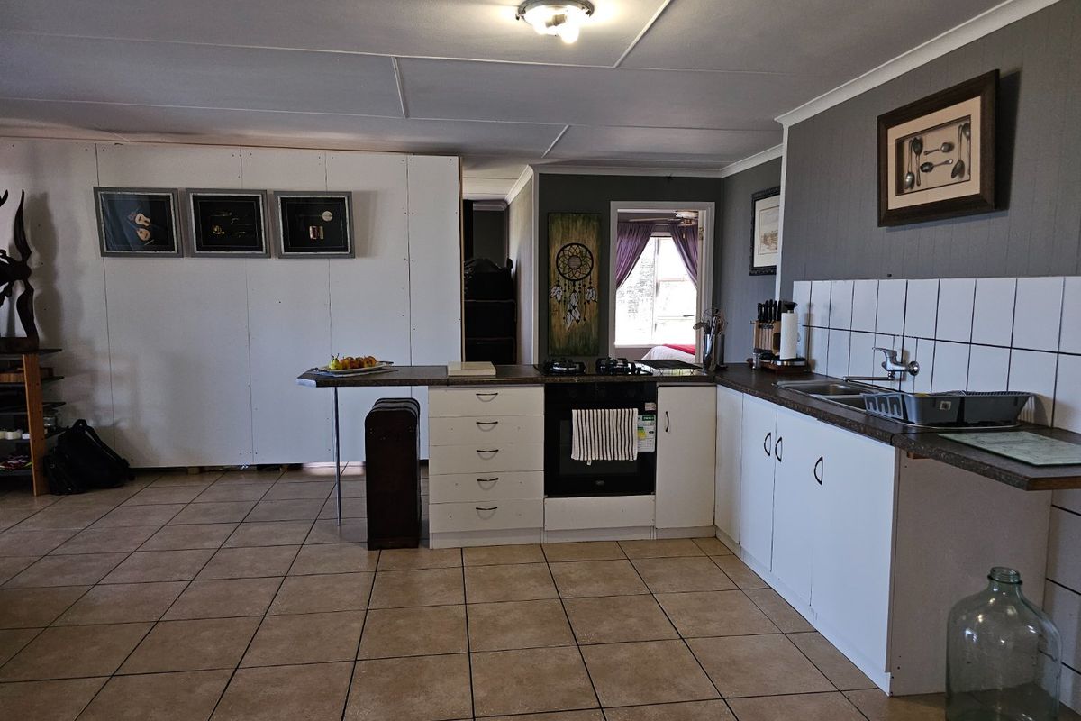Functional kitchen area featuring tiled flooring, built-in oven with gas hob, and white cabinetry with a tiled backsplash.