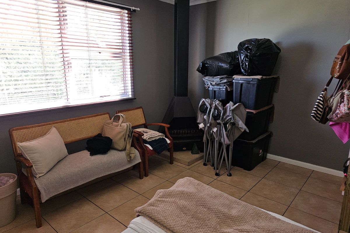 Living room featuring a freestanding fireplace, tiled flooring, and large windows with venetian blinds, offering a functional space with potential for modernization.
