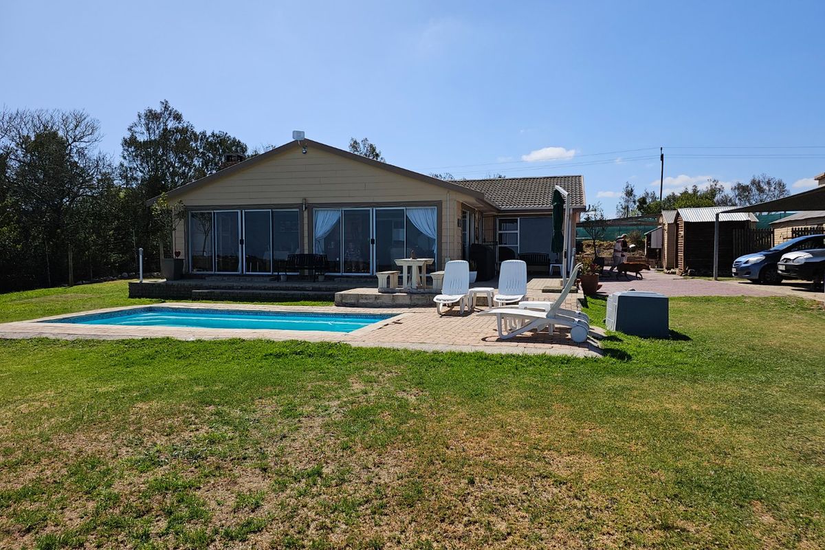 Rear view of the farmhouse featuring a swimming pool, paved patio area, and large sliding glass doors leading into the main living space.