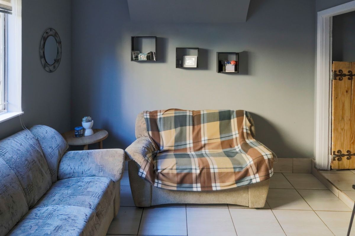 A living room area featuring tiled flooring and a distinctive wooden door with decorative metal hinges.