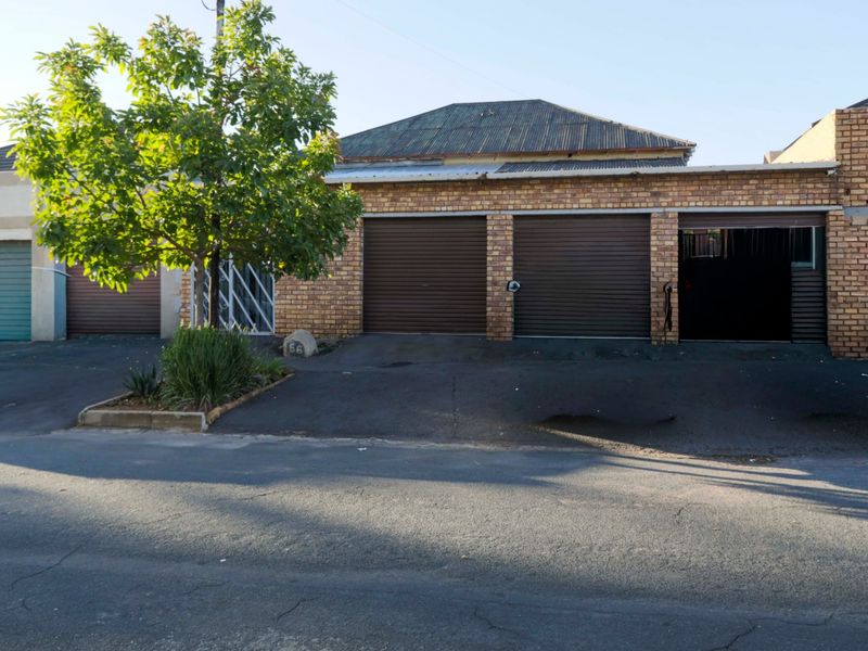 Front exterior view of a residential property featuring a triple garage with roller doors, brick facade, and an asphalt driveway.