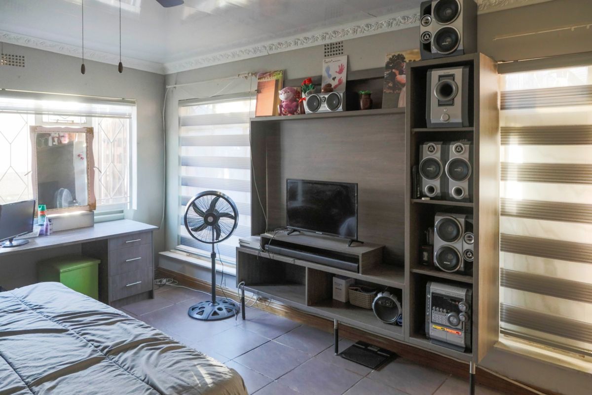 A bedroom featuring tiled flooring, built-in desk space, and a custom media unit with integrated shelving and storage.