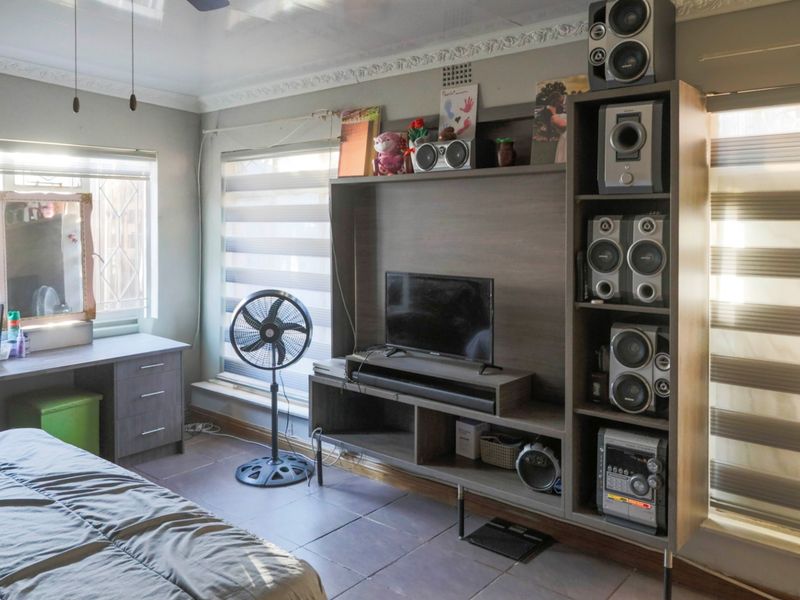 A bedroom featuring tiled flooring, built-in desk space, and a custom media unit with integrated shelving and storage.