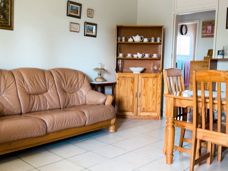 Open plan living and dining area featuring neutral tiled flooring and an arched transition to the kitchen space.