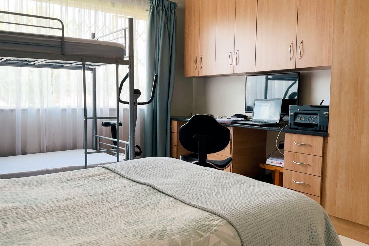 A functional bedroom featuring extensive built-in wooden cabinetry and a integrated desk area, providing ample storage and workspace.