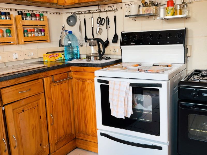 A functional kitchen featuring wooden cabinetry, tiled backsplash, and dual freestanding stoves, offering a dated aesthetic with potential for modern updates.