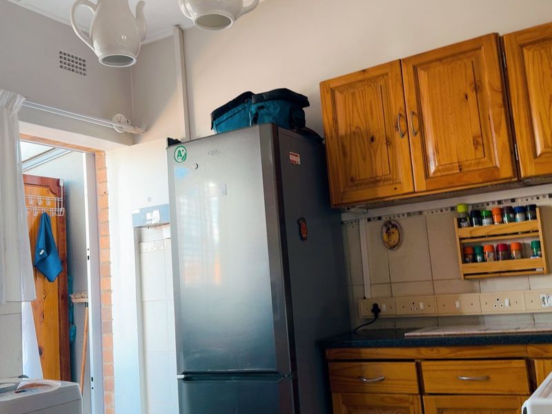 A functional kitchen featuring traditional wooden cabinetry, tiled backsplash, and laminate countertops, offering a classic layout with potential for modern updates.