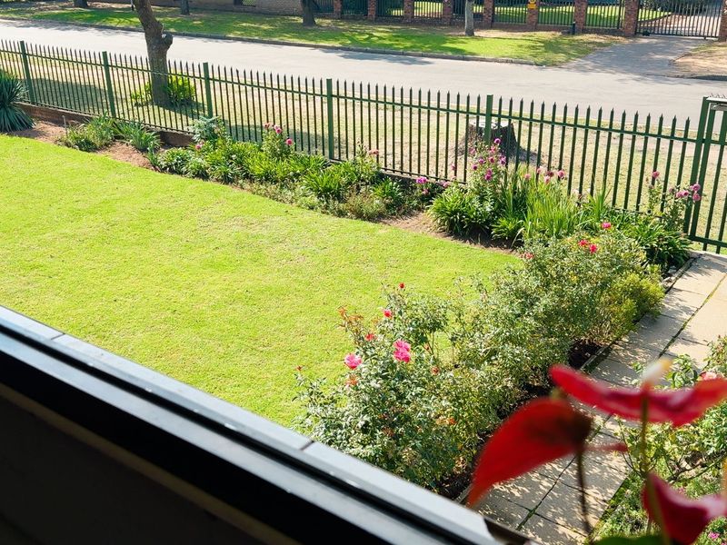 Elevated view overlooking a well-maintained private garden with a paved walkway and secure metal perimeter fencing.