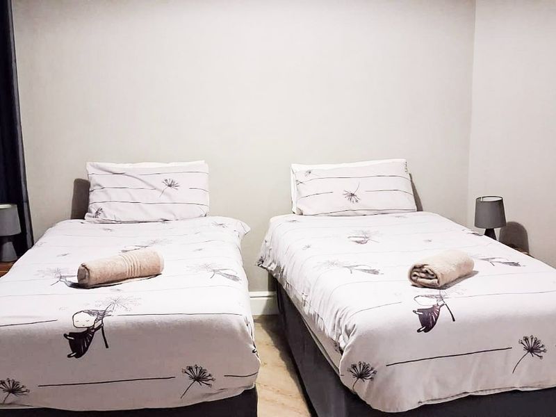 A bedroom featuring neutral wall tones and skirting boards, currently configured with two single beds.