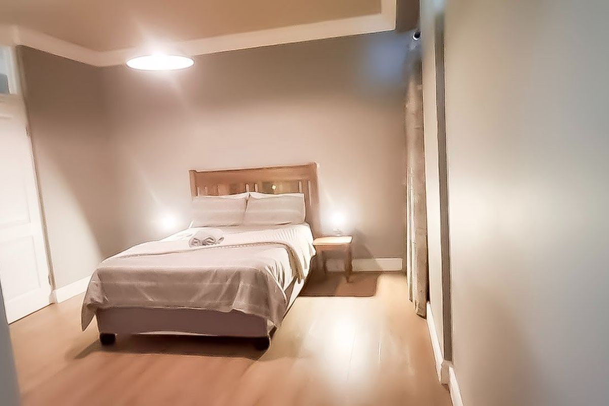 A well-maintained bedroom featuring neutral wall tones, laminate flooring, and coved ceiling details, providing a clean and comfortable living space.