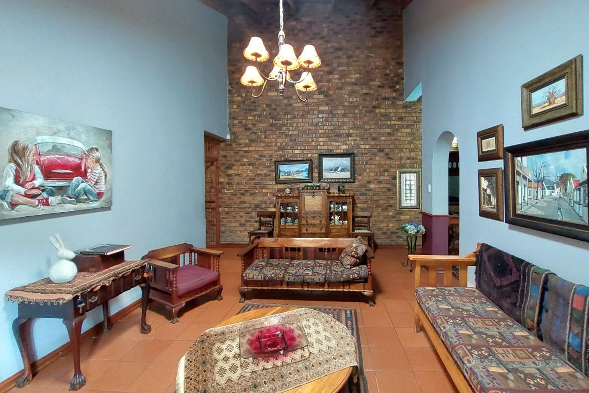 Spacious living room featuring a high exposed timber beam ceiling, a prominent face brick feature wall, and traditional terracotta floor tiles.