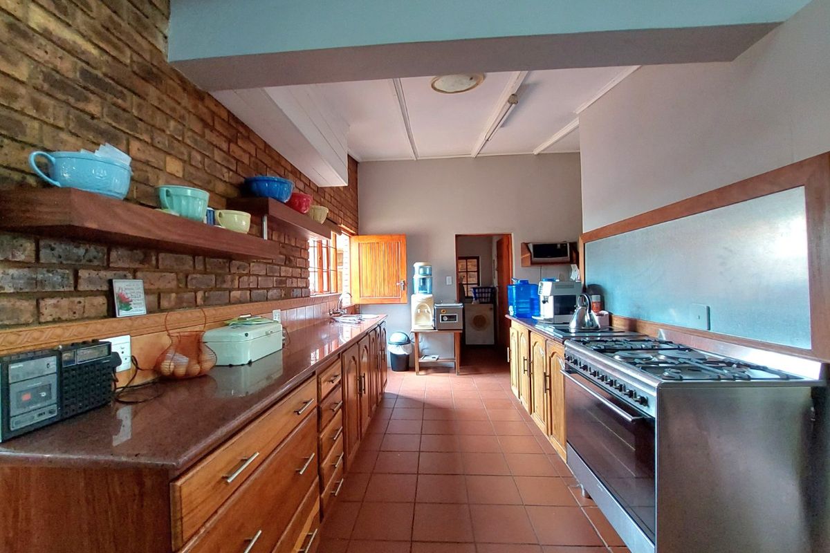 A functional kitchen featuring exposed brick walls, wooden cabinetry, stone benchtops, and a gas stove, with direct access to a laundry area.