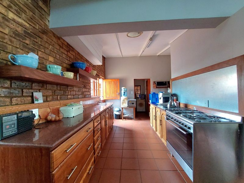 A functional kitchen featuring exposed brick walls, wooden cabinetry, stone benchtops, and a gas stove, with direct access to a laundry area.