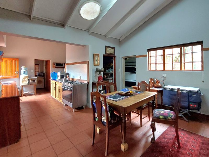 Open-plan kitchen and dining area featuring vaulted ceilings, a skylight, terracotta flooring, and an exposed brick feature wall.