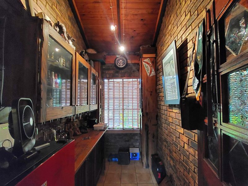A rustic bar area featuring exposed brick walls, timber ceiling, and built-in timber cabinetry with a matching countertop.