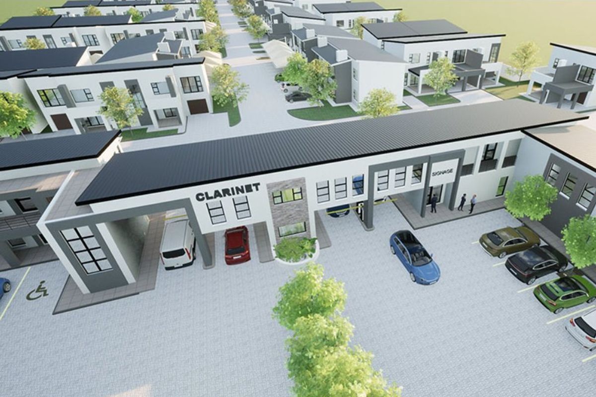 An aerial view of a modern townhouse development complex featuring paved parking areas, landscaped surroundings, and contemporary architectural building designs.