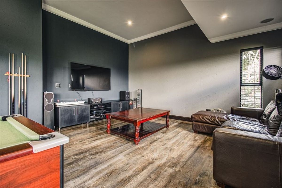 A spacious living area featuring modern laminate flooring, recessed downlighting, and dark accent walls, creating a comfortable space for entertainment and relaxation.