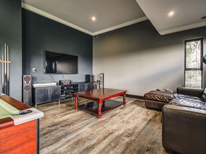 A spacious living area featuring modern laminate flooring, recessed downlighting, and dark accent walls, creating a comfortable space for entertainment and relaxation.