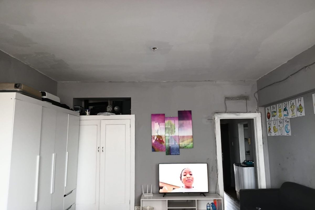 A living room area featuring built-in cabinetry, grey painted walls, and an adjacent doorway leading to a utility space.