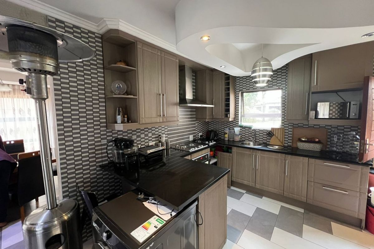 Modern kitchen featuring wood-finish cabinetry, granite countertops, a gas hob, and a unique recessed ceiling design with integrated lighting.