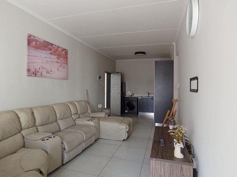 Open plan living area featuring tiled flooring and a compact kitchenette with integrated laundry plumbing and cabinetry.