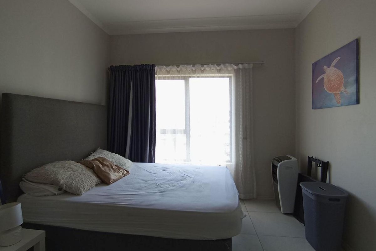 A bedroom featuring tiled flooring, a sliding window with curtains, and cove cornicing, providing a functional and neutral living space.