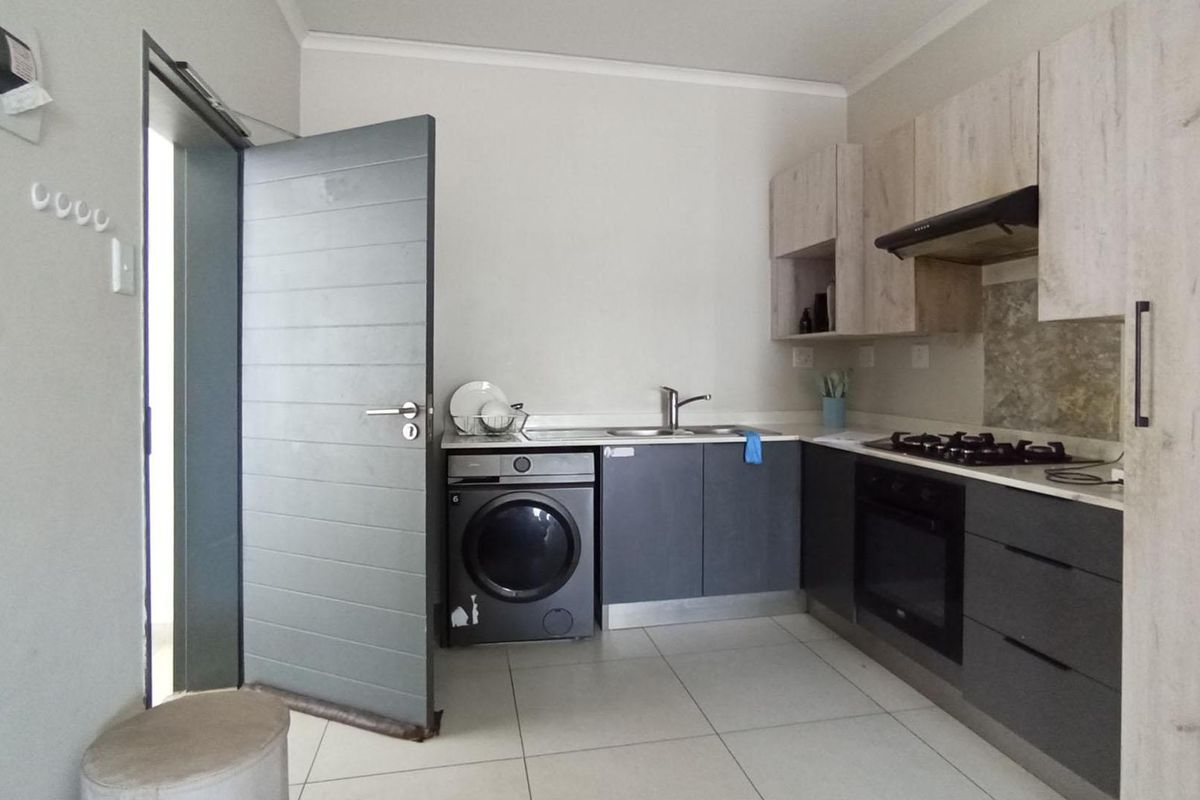 Modern kitchen featuring two-tone cabinetry, integrated gas hob, electric oven, extractor fan, and space for a washing machine.
