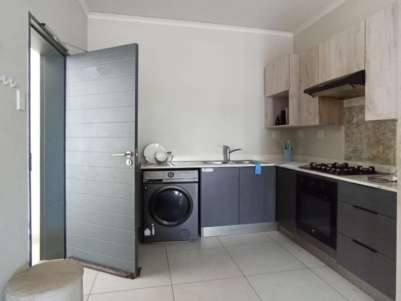 Modern kitchen featuring two-tone cabinetry, integrated gas hob, electric oven, extractor fan, and space for a washing machine.