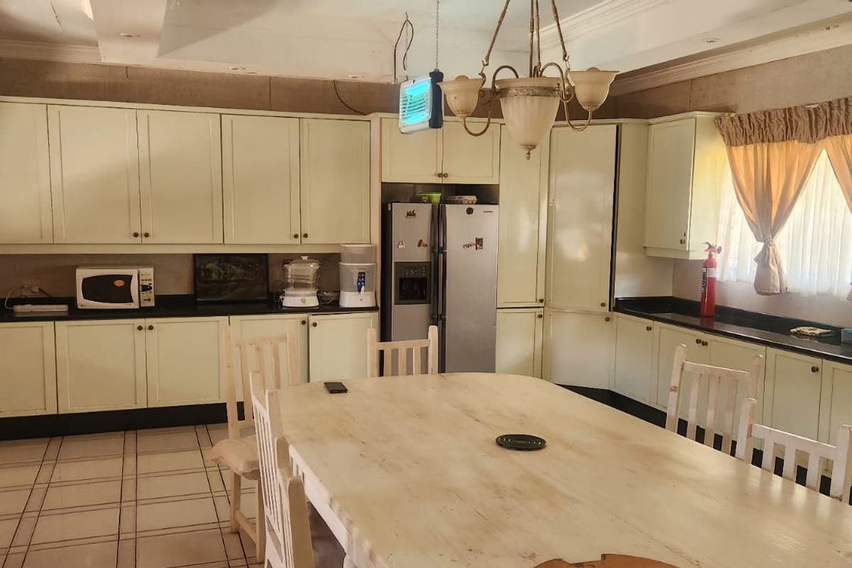 Spacious farmhouse kitchen featuring extensive built-in cabinetry, granite countertops, tiled flooring, and a dedicated dining area with a classic chandelier.