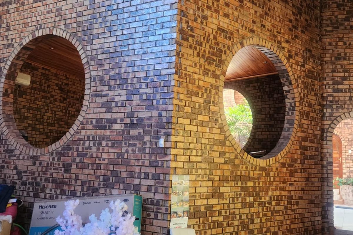 A unique living space featuring distinctive exposed brick walls, circular architectural windows, and an arched entryway with warm timber ceiling accents.