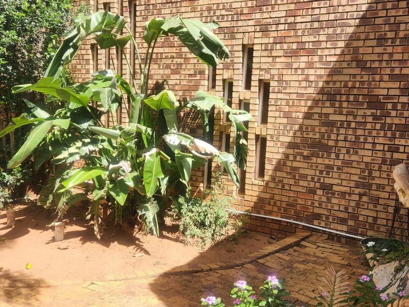 A rear exterior view of the property featuring a face brick wall with decorative vertical slit windows and a paved garden pathway.