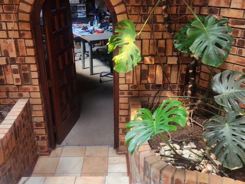 A rustic outdoor patio area featuring exposed brick walls, arched entryway, and built-in brick planters, providing a charming transition to the interior space.
