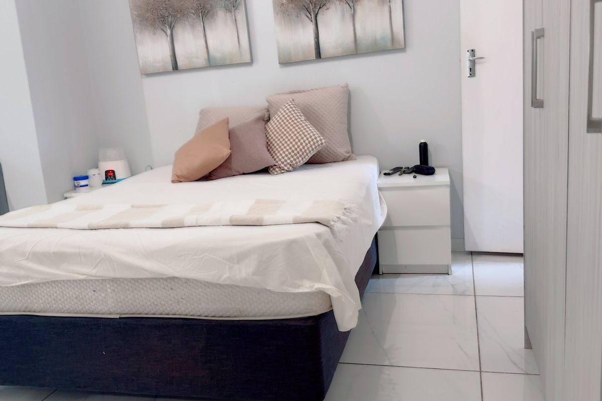 A well-maintained bedroom featuring light-colored tiled flooring and a built-in wardrobe, offering a clean and functional living space.