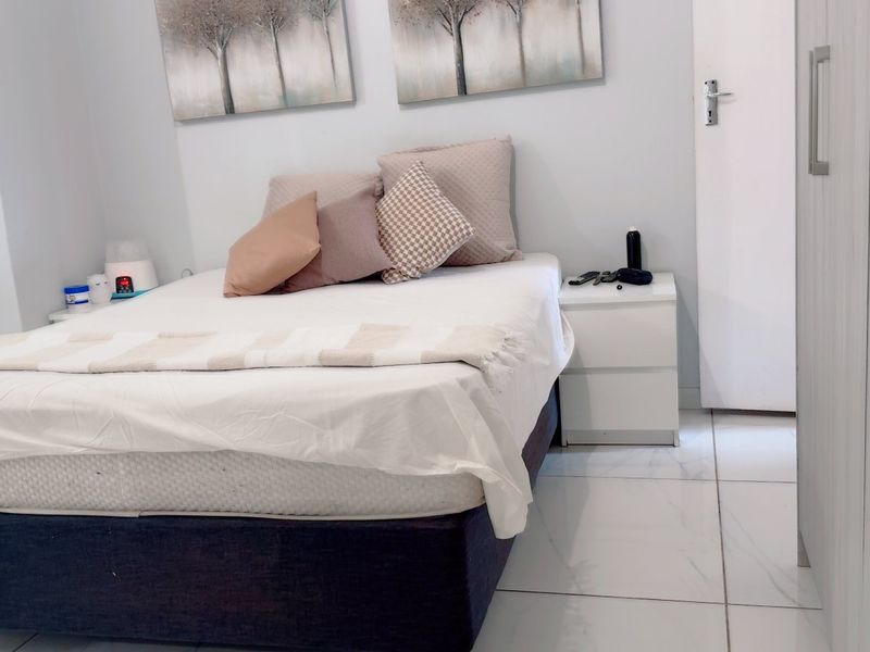 A well-maintained bedroom featuring light-colored tiled flooring and a built-in wardrobe, offering a clean and functional living space.