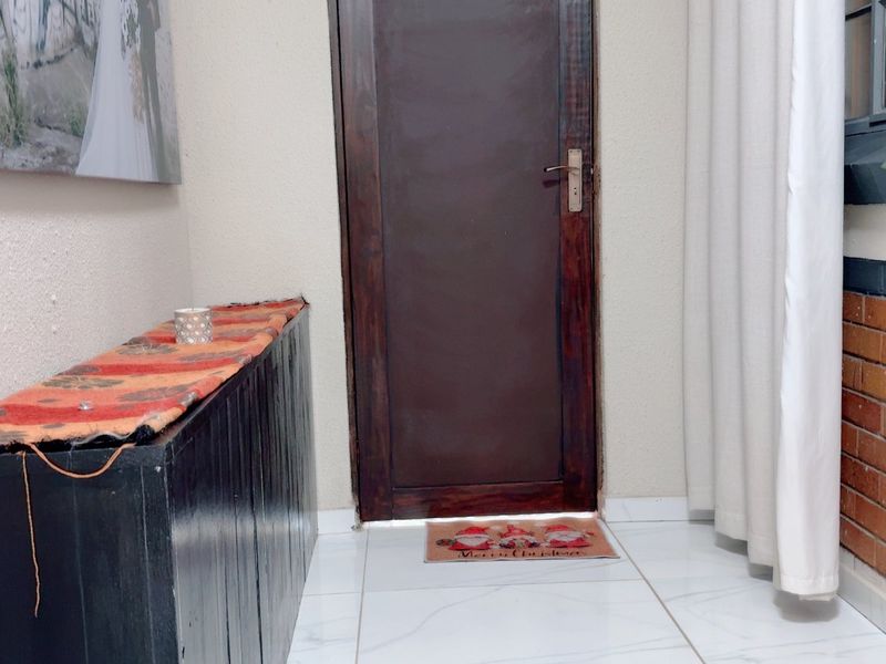 An entry area featuring tiled flooring, a timber door, and a combination of textured and exposed brick wall finishes.