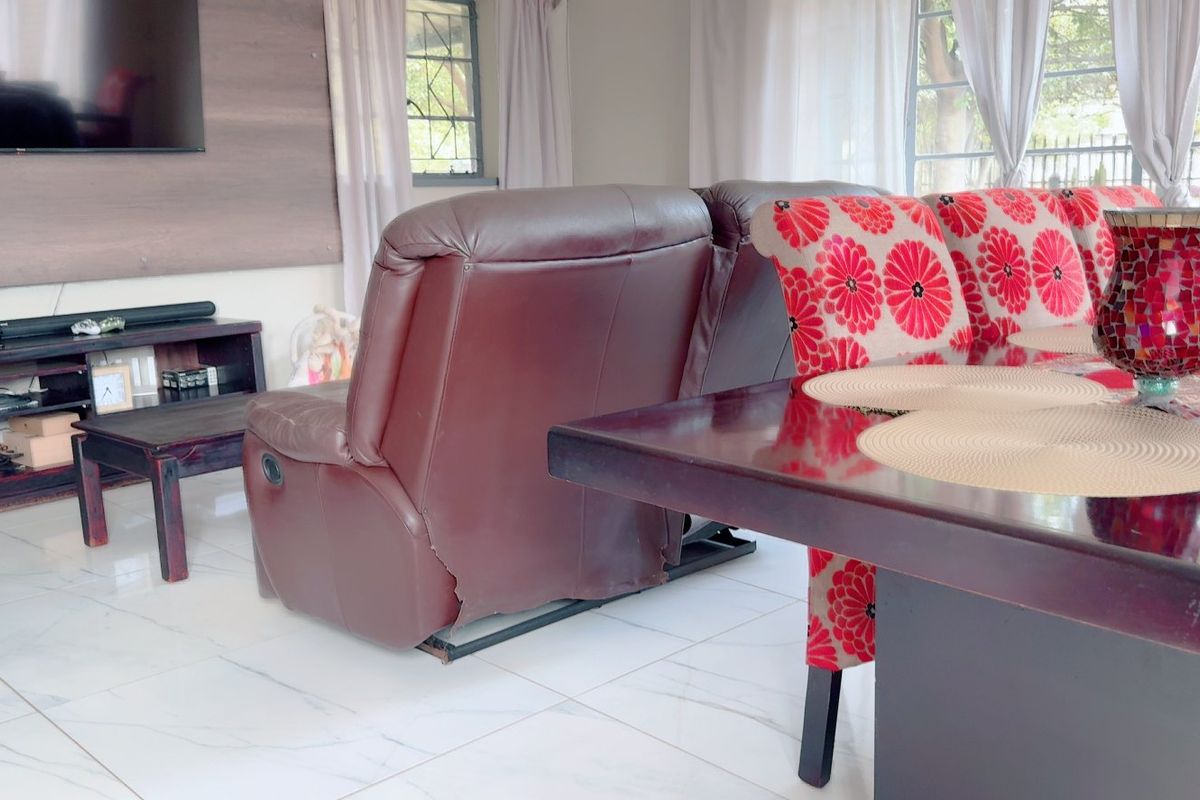 A living room area featuring light-colored tiled flooring and a wall-mounted television, providing a functional space for relaxation and entertainment.