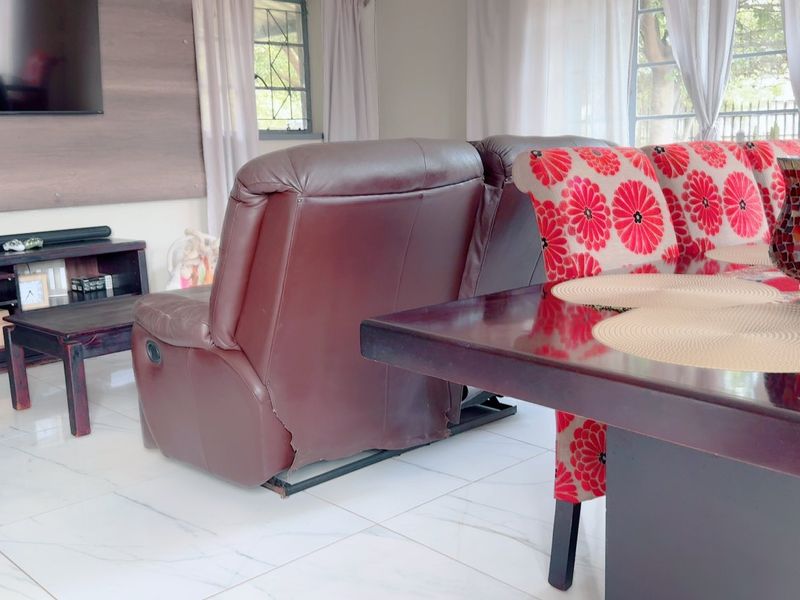 A living room area featuring light-colored tiled flooring and a wall-mounted television, providing a functional space for relaxation and entertainment.