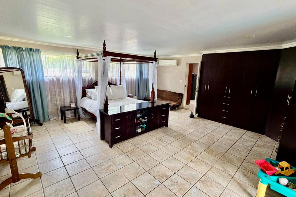 Spacious bedroom featuring large built-in cupboards, tiled flooring, and an exposed brick feature wall, providing a solid foundation for modern interior updates.