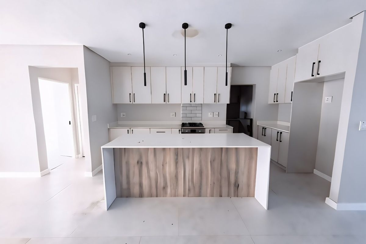 Modern kitchen featuring a central island with wood-grain detailing, stone countertops, built-in cabinetry, gas hob, and stylish pendant lighting in a clean, neutral space.