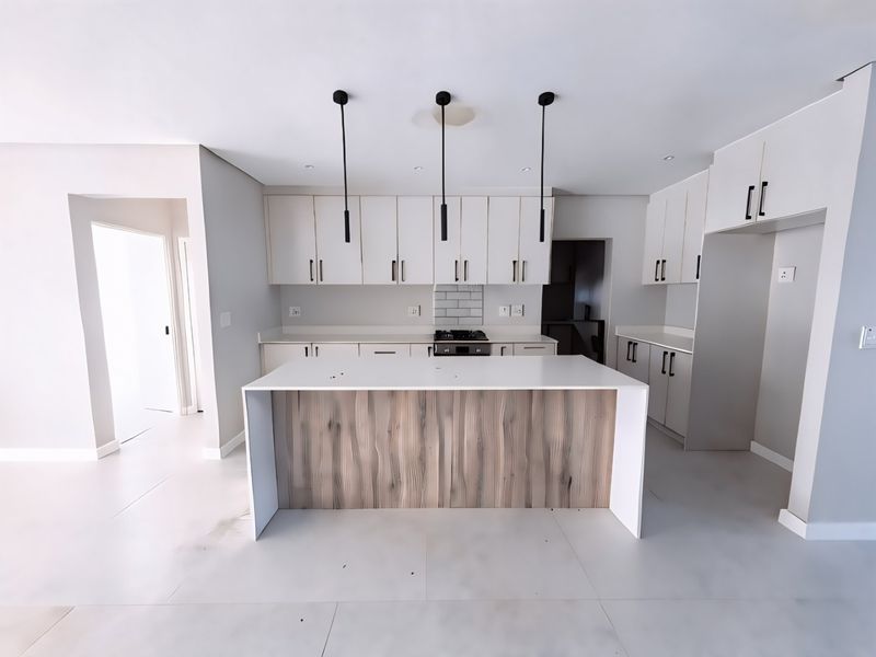Modern kitchen featuring a central island with wood-grain detailing, stone countertops, built-in cabinetry, gas hob, and stylish pendant lighting in a clean, neutral space.
