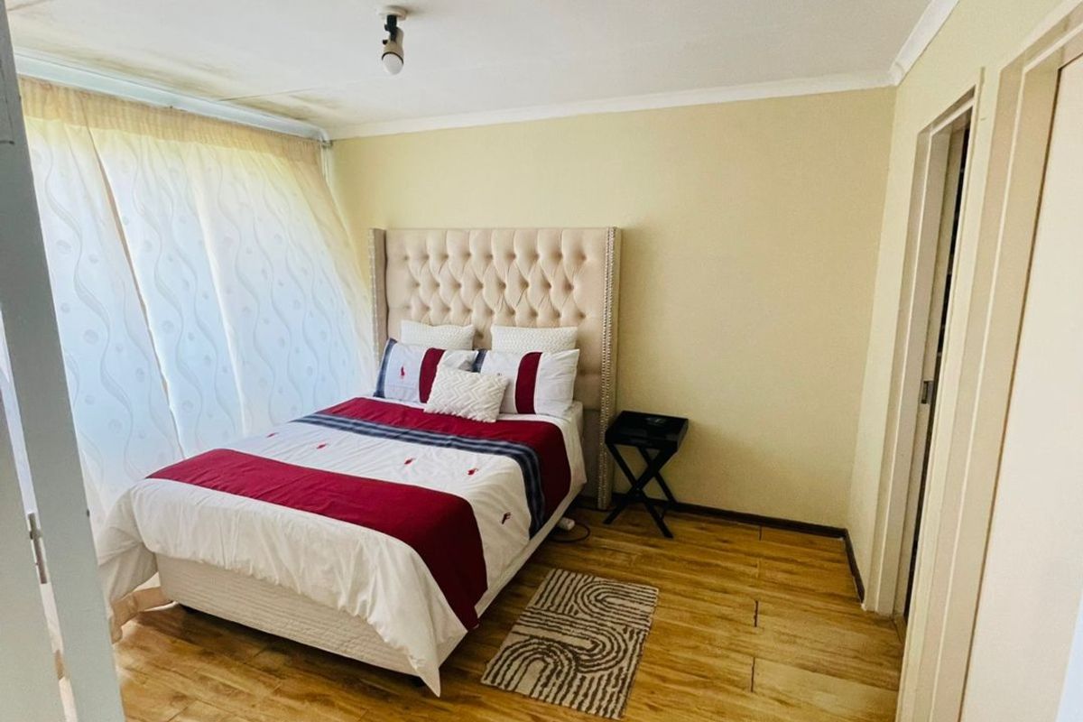 A bedroom featuring wood-look tile flooring and neutral wall tones, providing a functional space with potential for cosmetic updates to the ceiling and finishes.