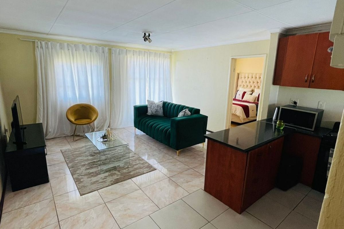 Open plan living area featuring tiled flooring and a compact kitchen with dark wood cabinetry and granite countertops.