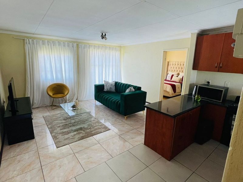 Open plan living area featuring tiled flooring and a compact kitchen with dark wood cabinetry and granite countertops.