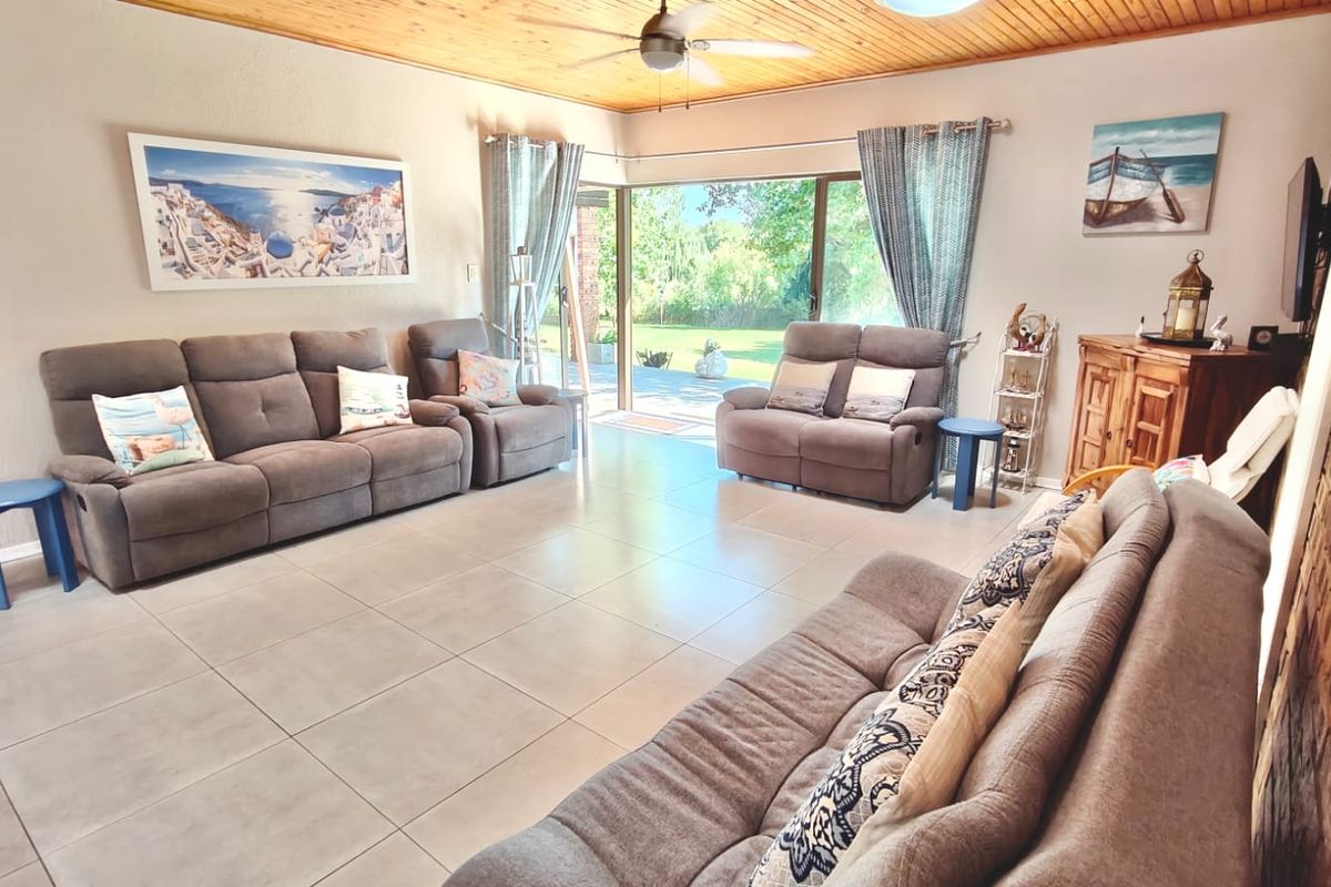 Spacious living room featuring tiled floors, a timber-clad ceiling with a fan, and large sliding doors providing direct access to the rear garden.